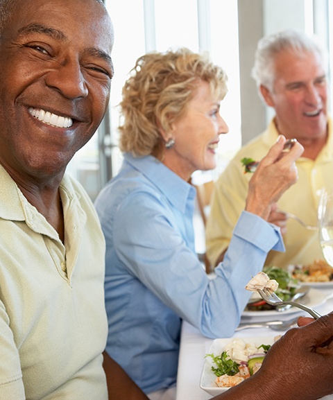 Implant denture patient in Mayfield smiling with friends